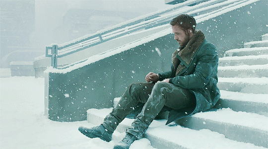 GIF image from Blade Runner 2049 K lies on the steps as the snow falls—cold, silent, and indifferent